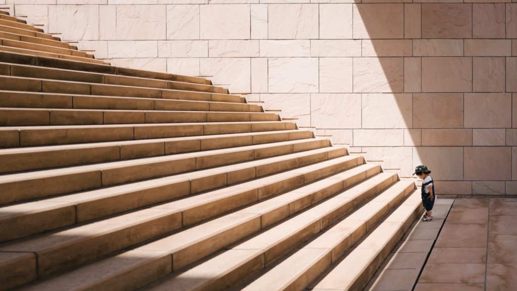 small child looking at first step of large staircase