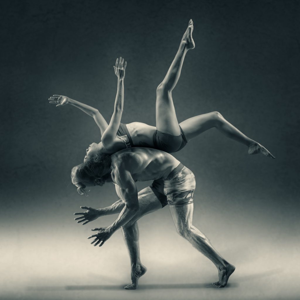 Man balancing women on his back. Both showing flexibility